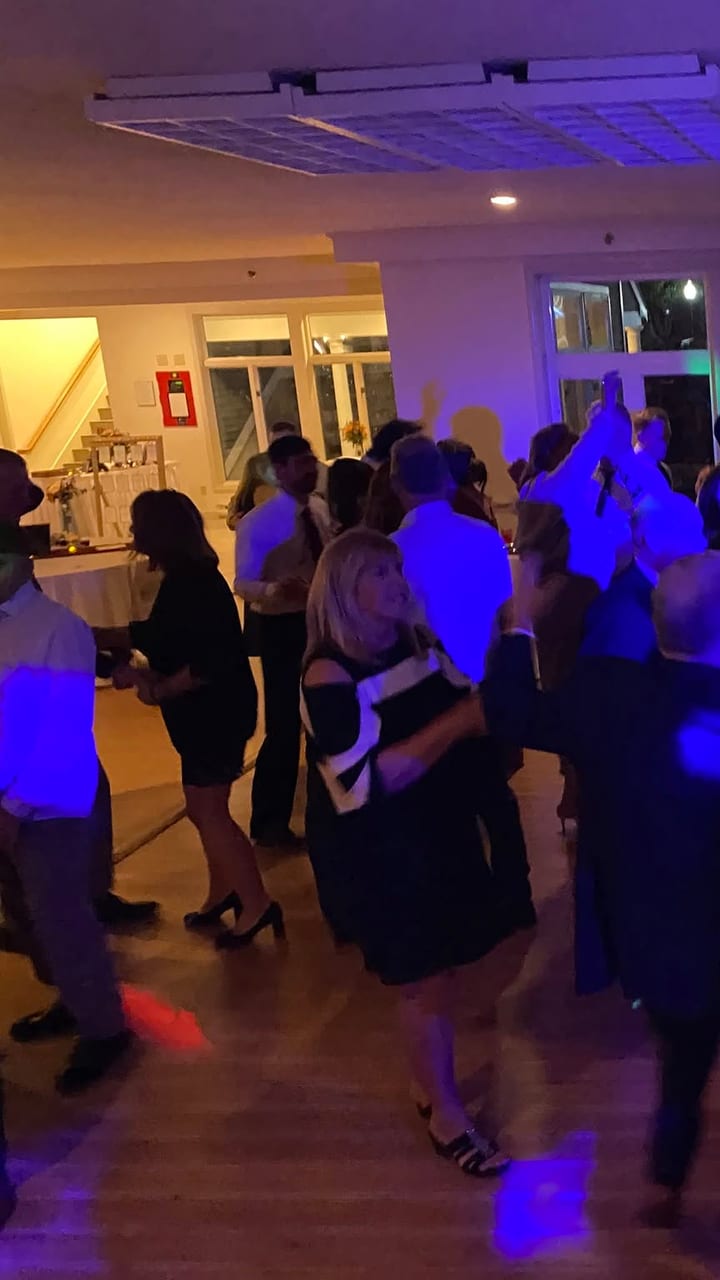 A packed wedding dance floor under blue light